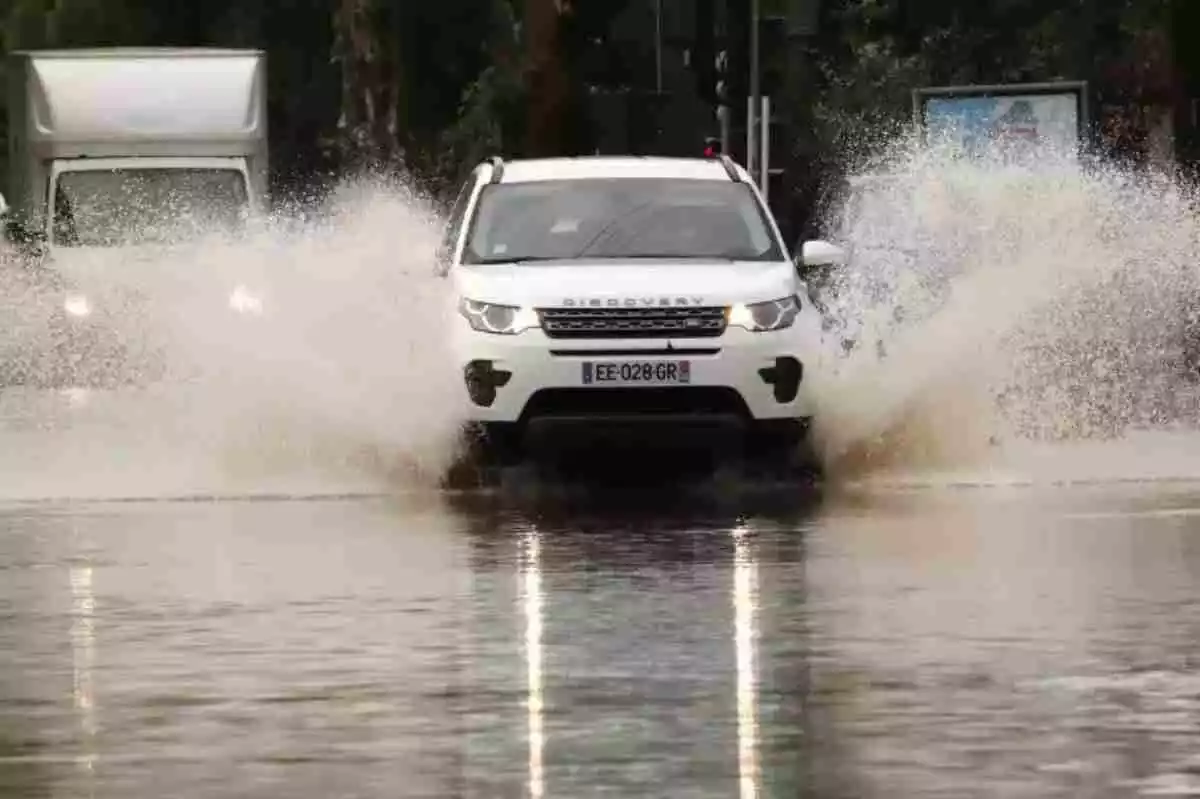 Imagen de un coche transitando por una vía inundada