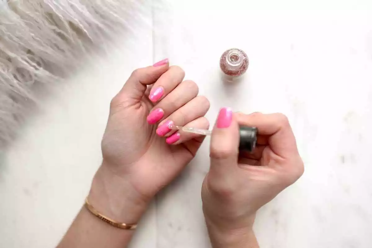 Mujer pintándose las uñas de color rosa