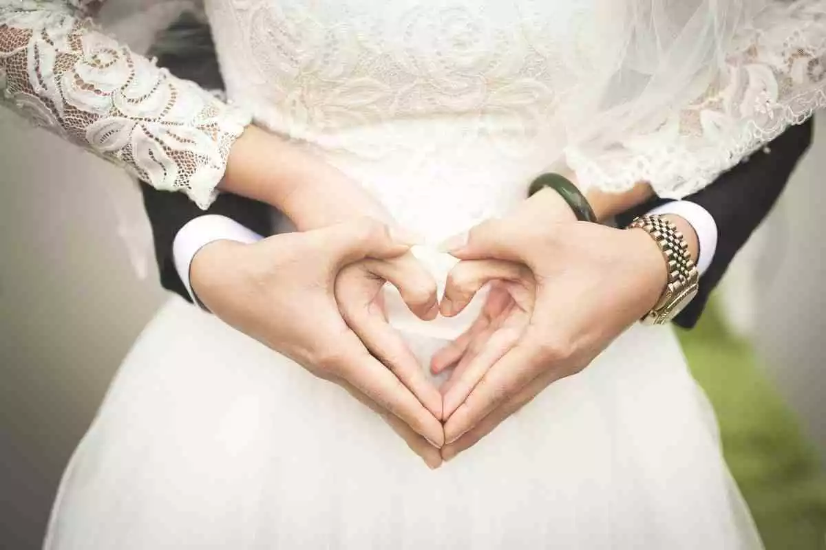 Novios en una boda formando un corazón con las manos