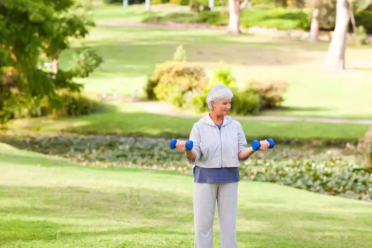 Jubilada haciendo ejercicio en un parque con unas pesas