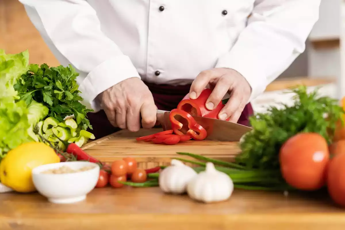 Fotografía de una persona cortando verduras en la cocina