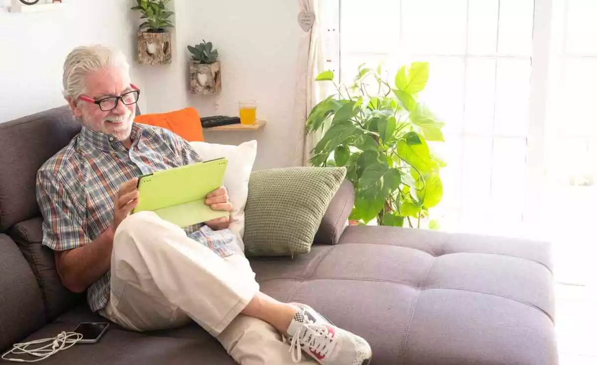 Abuelo mayor sentado en el sofá usando computadora portátil