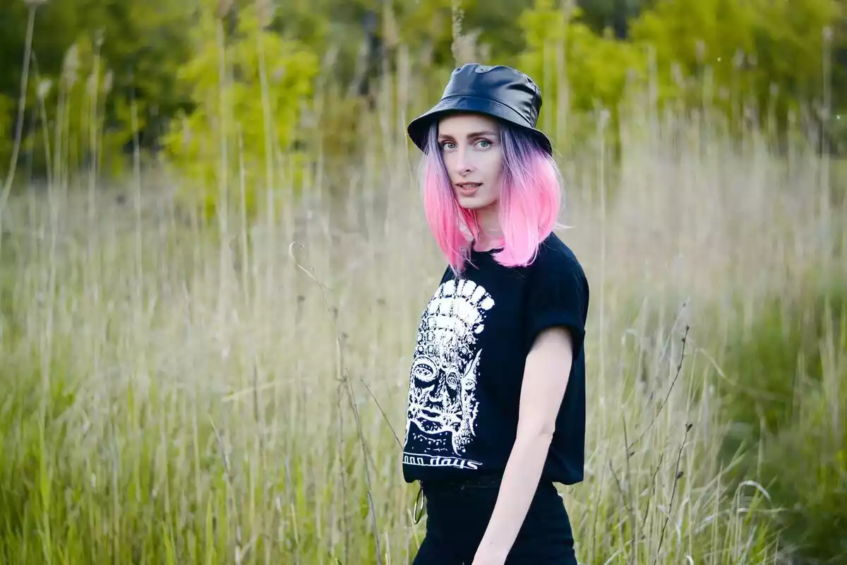 Chica con el pelo pintado de rosa plano medio con fondo verde naturaleza