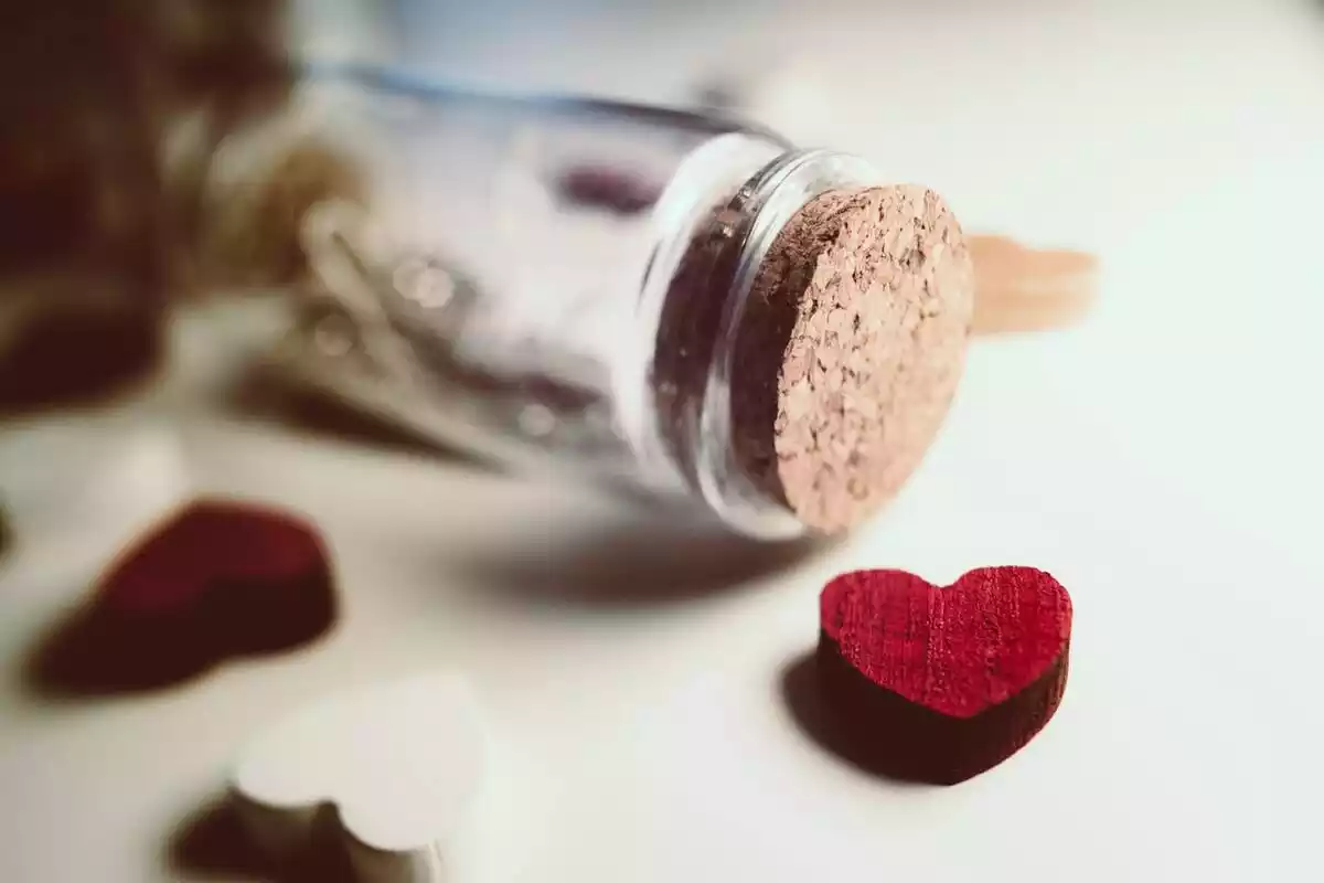 Detalle de corazones de madera con tapón de corcho y botella de cristal