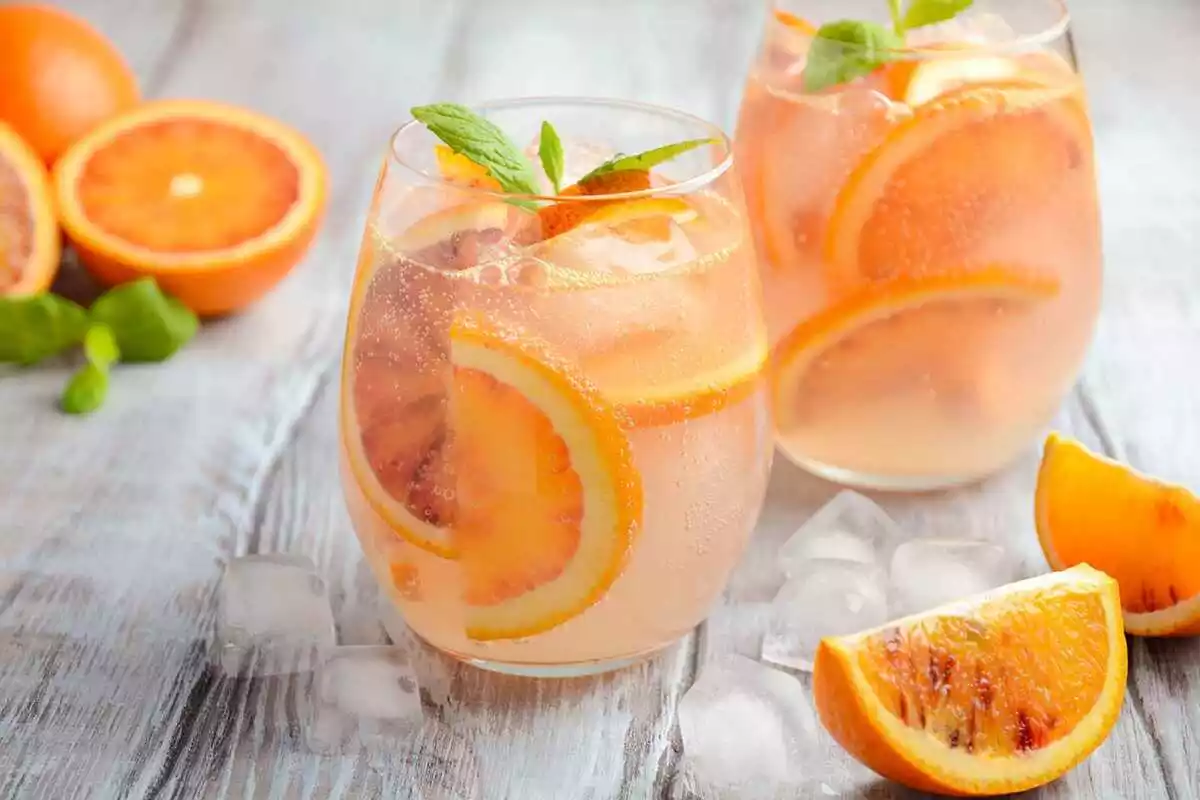 Frío refrescante bebida con rodajas de naranja de sangre en una copa sobre un fondo de madera