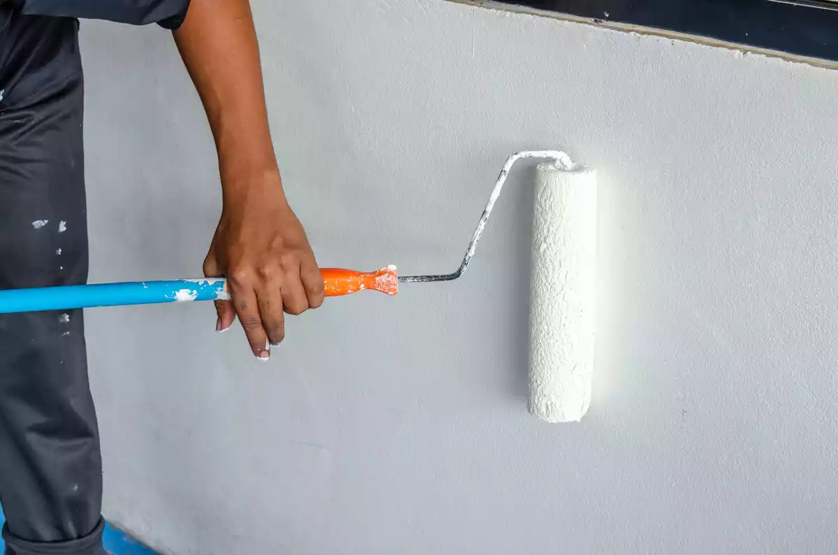 Rodillo pintando una pared de color blanco