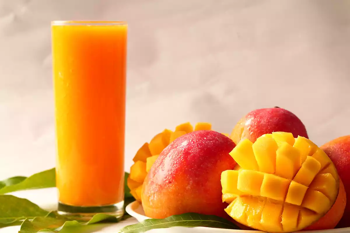 Un vaso de mango con las piezas de fruta al lado