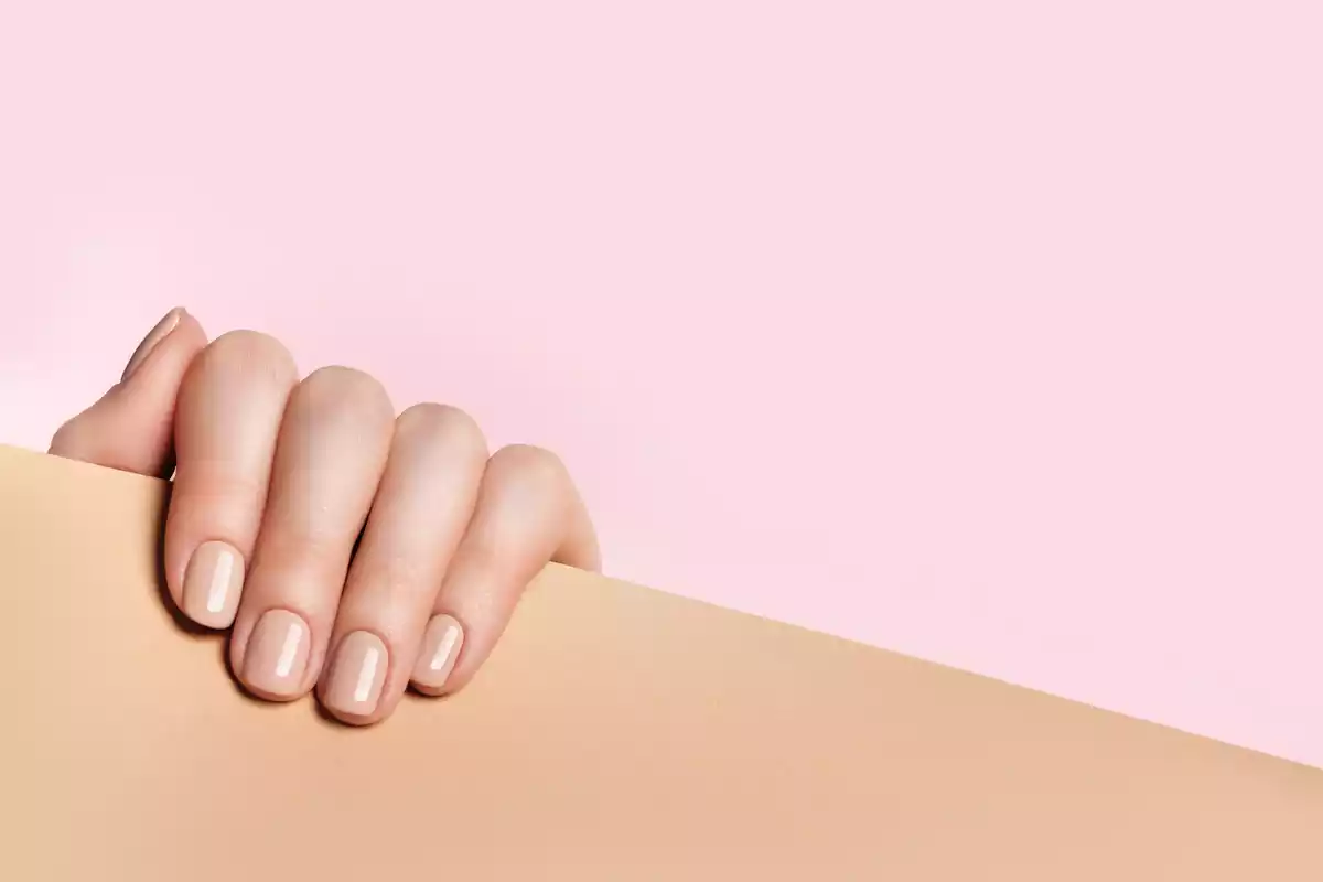 Una mano mostrando las uñas de color nude