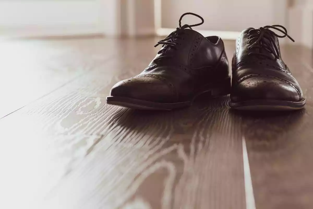 Zapatos oxford oscuros sobre un suelo de madera