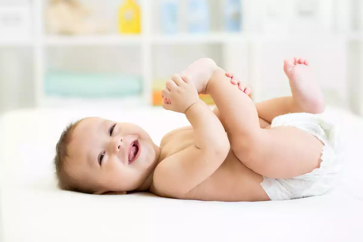 Bebé sonriente cogiéndose el pie