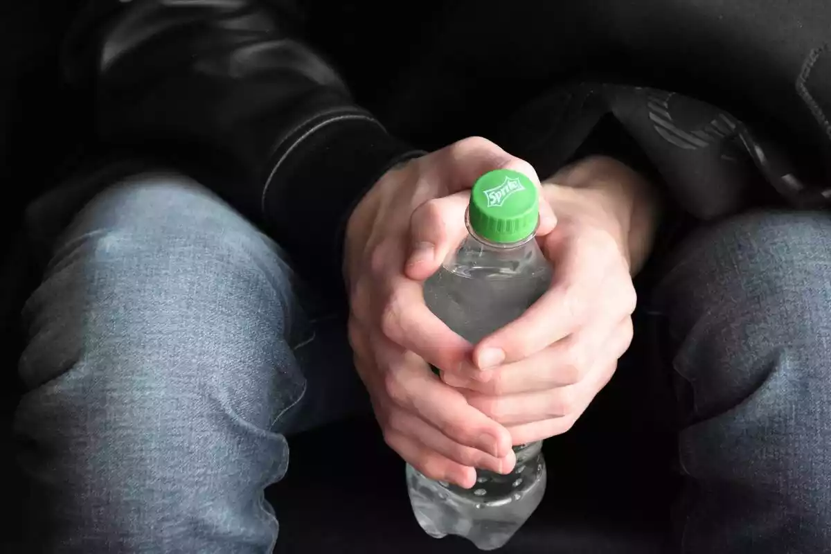 Botella de plástico entre unas manos de hombre