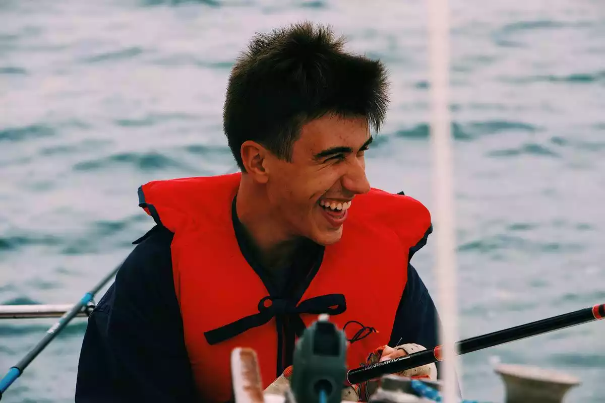 chico muy sonriente en alta mar pescando con chaleco salvavidas puesto