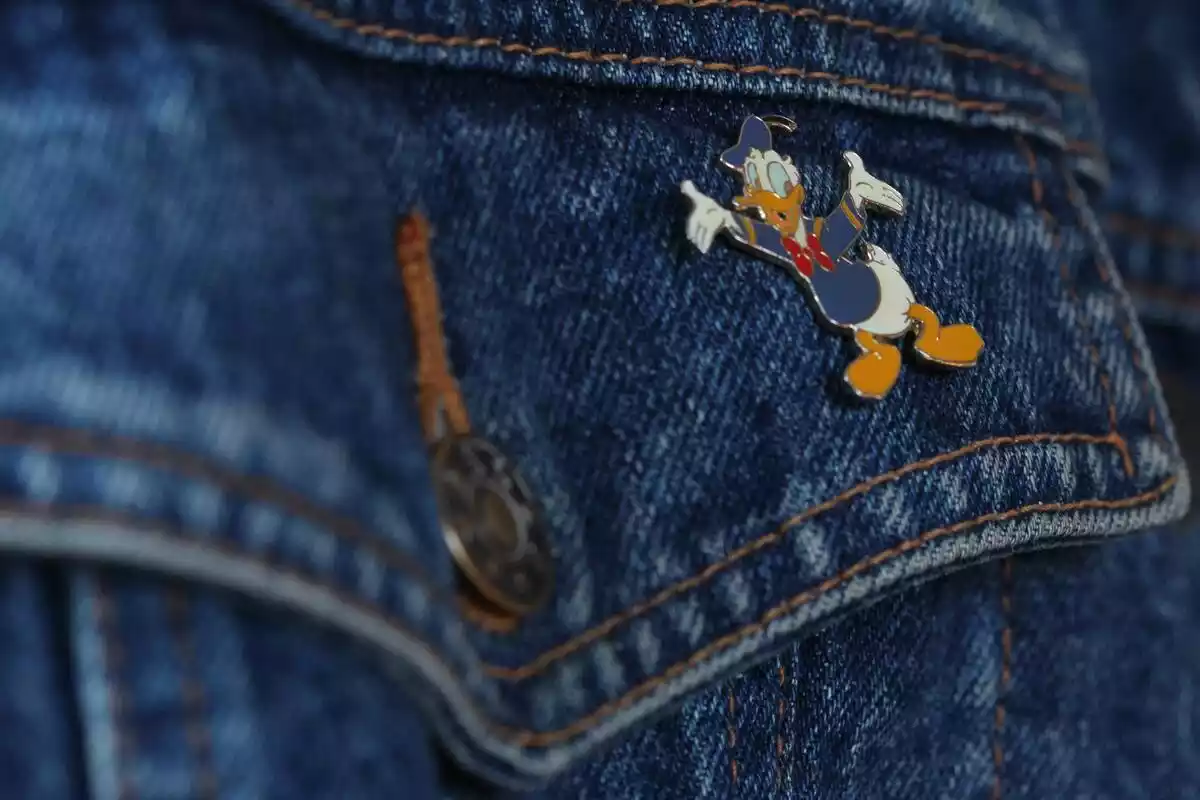 Detalle de bolsillo de ropa tejana con pin de Pato Donald