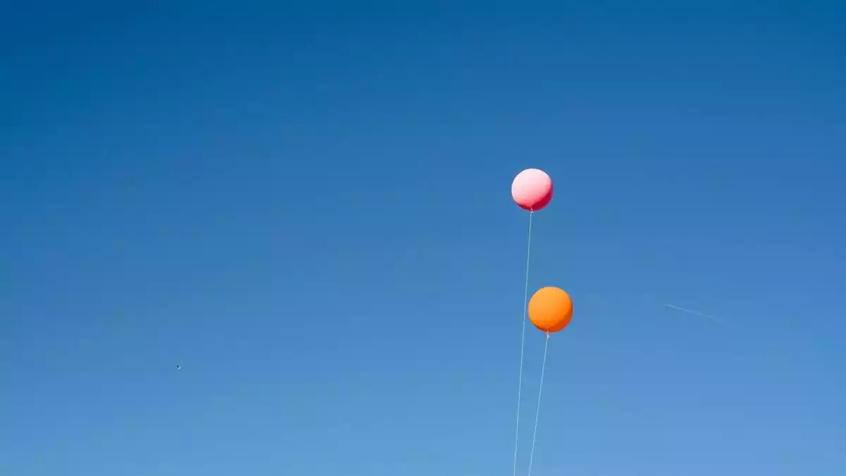 dos globos con hilo volando sobre fondo de cielo