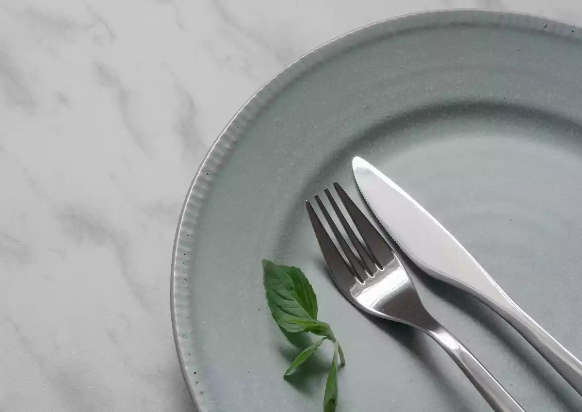 tenedor y cuchillo en un plato sobre mesa blanca de mármol