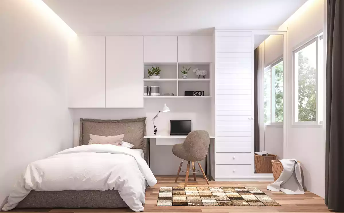 Un dormitorio con una cama, un escritorio, un armario y una ventana