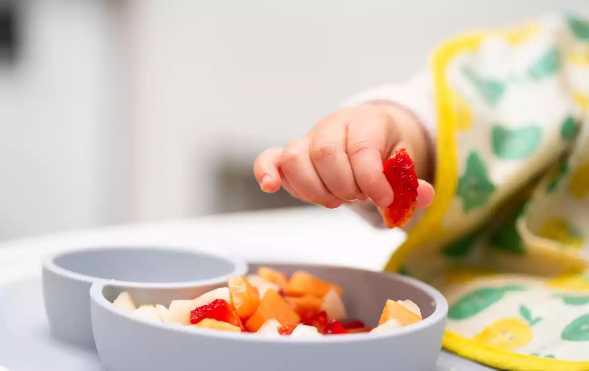 Un niño cogiendo fruta de un bol