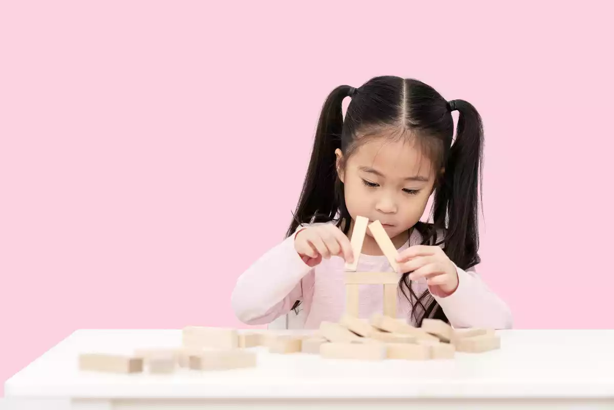 Una niña china jugando con bloques de madera